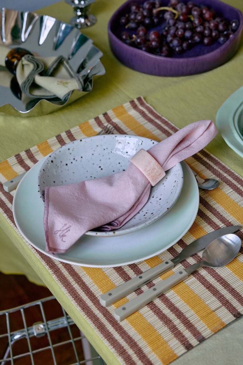 Dekoration Elegant Tischgedeck mit Tellern, Besteck und violetten Trauben in einer Schüssel.