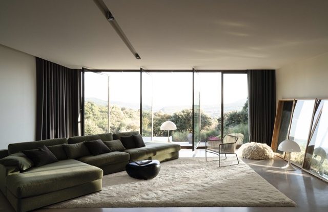 Modern Wohnbereich mit großem Fenster, bequemer Couch und Teppich. Naturblick.