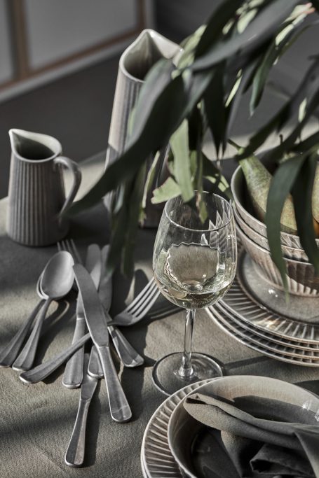 Elegant Tischgedeck mit Besteck, Gläsern und Geschirr in neutralen Farben.