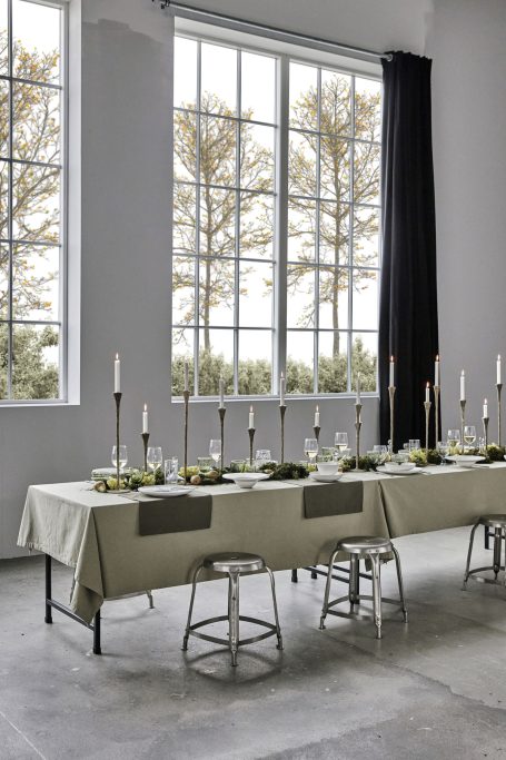 Modernes Esszimmer mit langen Tischen, Kerzen und Blick auf einen Garten.