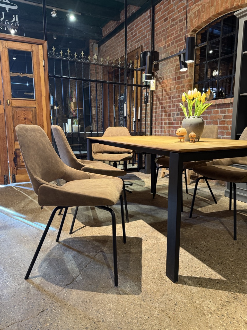 Stühle Moderne Essgruppe mit braunen Stühlen und einem Tisch, dekoriert mit Blumen und Obst.