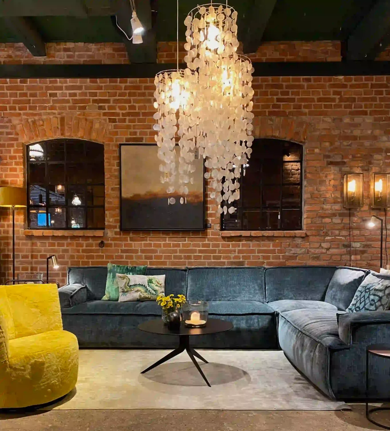 Sofas Wohnecke mit grauem Sofa, gelbem Sessel und moderner Deckenleuchte in Backsteinwand-Umgebung.