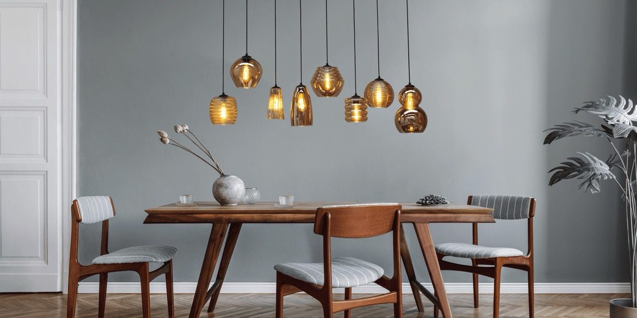 Moderne Esszimmer mit Holztisch, Stühlen und hängenden Lampen an grauer Wand.