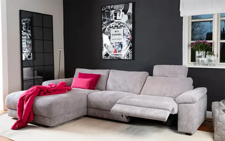 Beige, L-förmiges Sofa mit rotem Plaid in modernem Wohnzimmer. Schwarze Wand mit Kunstwerk.