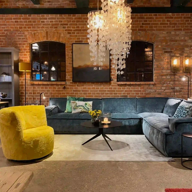 Moderner Wohnzimmerbereich mit blauer Couch, gelbem Sessel und einem auffälligen Kronleuchter.