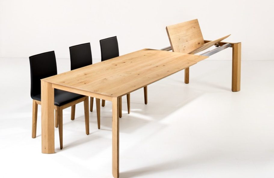 Holztisch mit drei schwarzen Stühlen, eine Tischplatte zur Erweiterung.