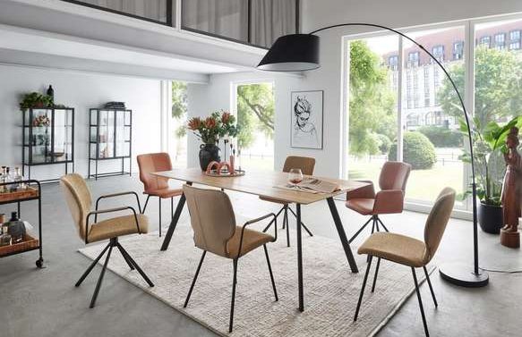 Moderne Esszimmermöbel mit einem Tisch, Stühlen und einer Stehlampe in hellem Raum.