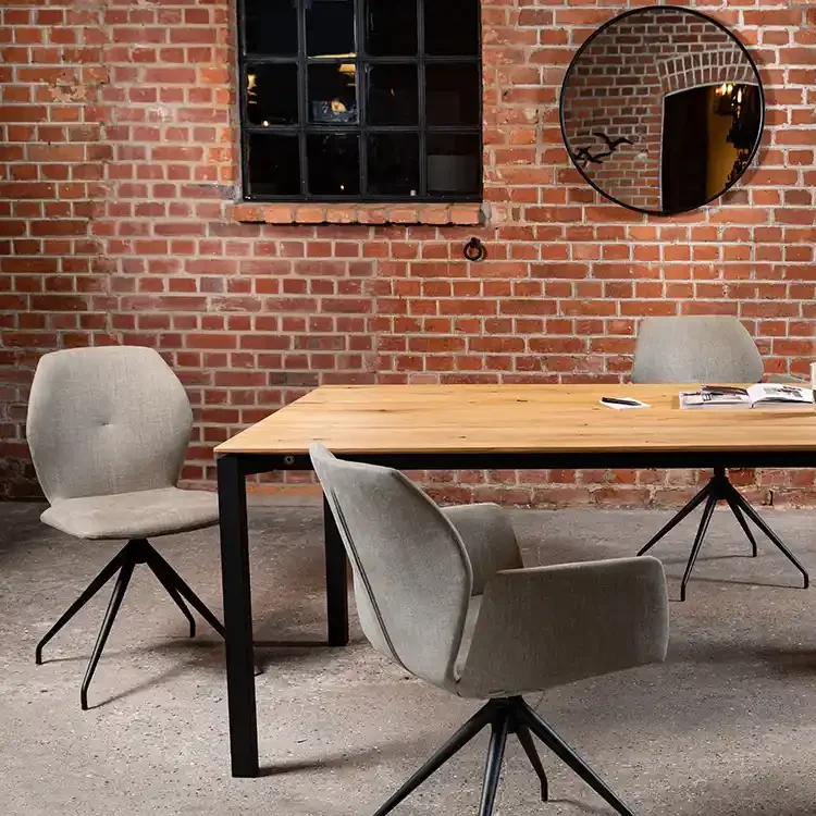 Moderne Einrichtung mit einem Holztisch, grauen Stühlen und einer Backsteinwand.